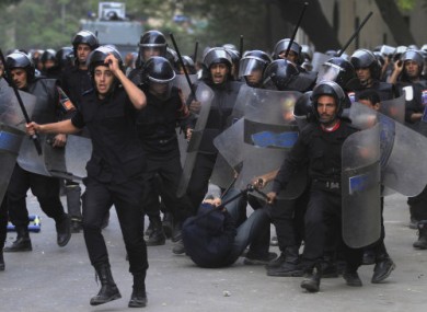 Egyptian police strike a protester during clashes in Tahrir Square today.