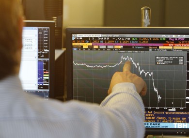 A trader points at a figure showing the fall of the euro in Paris following S&P's announcement