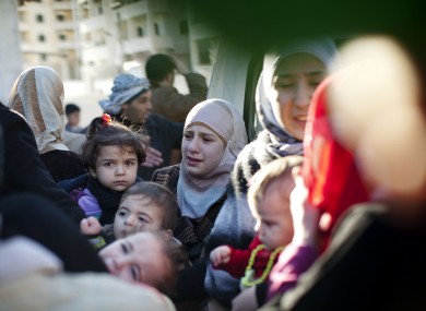 A family leaves their house after the building was hit by a Syrian army tank in Idlib, north Syria on Sunday.