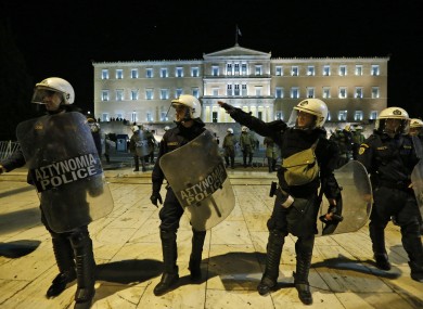 Greek riot police officers move to push anti austerity protesters off the street, in front of the Parliament in central Athens yesterday.
