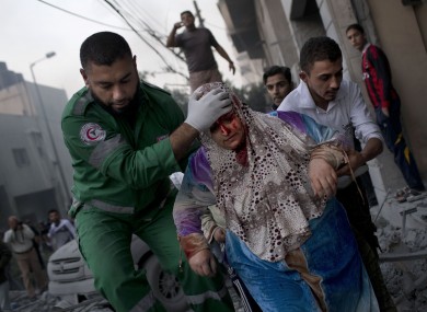A Palestinian woman is helped after being injured during an Israeli forces strike on a sports field next to her house in Gaza City.