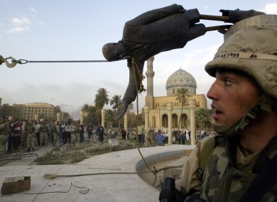 Iraqi civilians and U.S. soldiers pull down a statue of Saddam Hussein in downtown Baghdad after the US/British invasion in 2003.