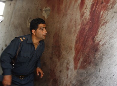 An Afghan policeman investigates the site after Taliban fighters attacked near Kabul airport this morning.
