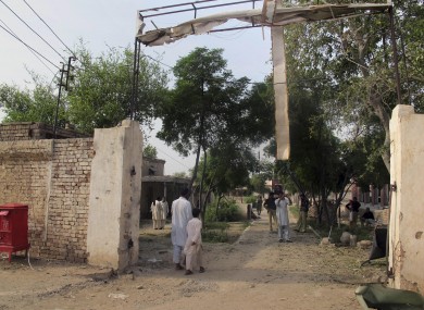 A plainclothes police officer takes a photo of the damaged prison gate